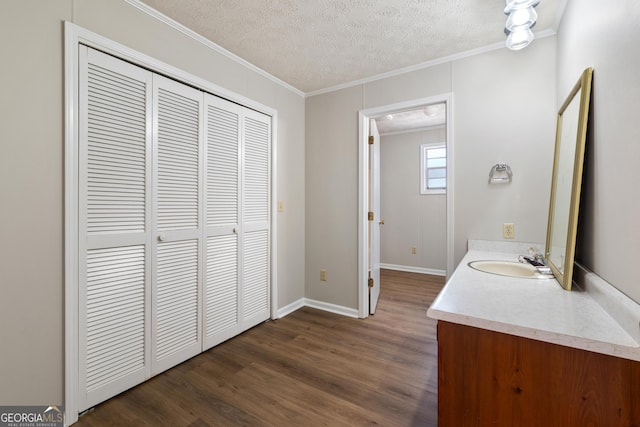 bathroom featuring crown molding, vanity, wood-type flooring, and a textured ceiling