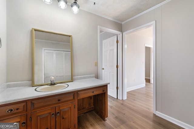 bathroom with crown molding, vanity, a textured ceiling, and hardwood / wood-style flooring