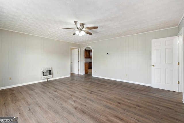 empty room featuring a textured ceiling, heating unit, ceiling fan, and dark wood-type flooring