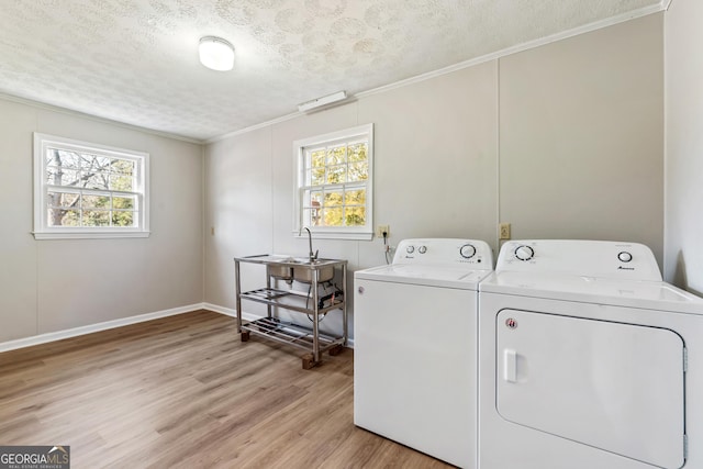 laundry area featuring a textured ceiling, washing machine and dryer, light hardwood / wood-style flooring, and a healthy amount of sunlight