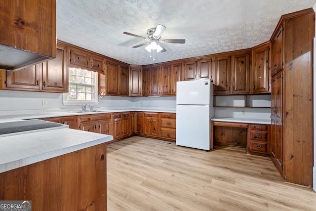 kitchen featuring a textured ceiling, white fridge, light hardwood / wood-style floors, and sink