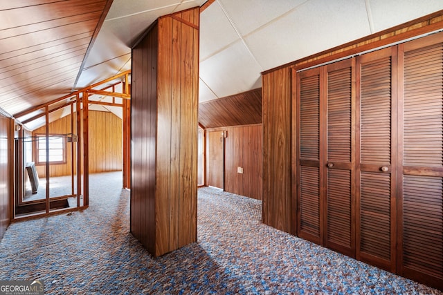 bonus room featuring carpet flooring, vaulted ceiling, and wooden walls