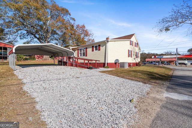 view of side of home with central AC, a carport, and a lawn