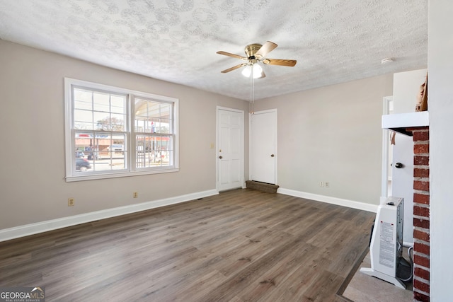 unfurnished room with a textured ceiling, heating unit, ceiling fan, and dark wood-type flooring