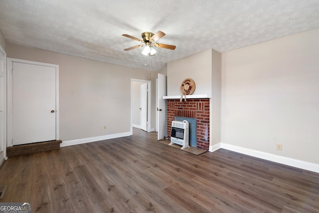 unfurnished living room with heating unit, a wood stove, a textured ceiling, and dark wood-type flooring