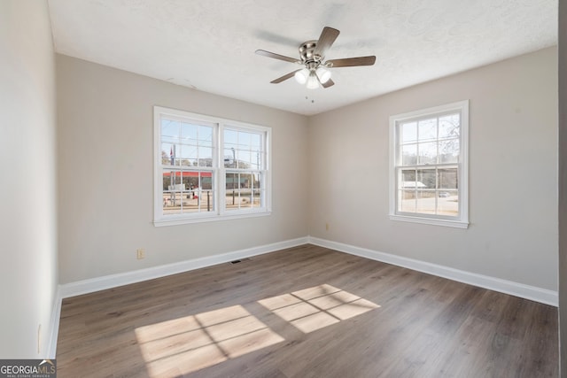 spare room with dark hardwood / wood-style floors, ceiling fan, and a textured ceiling