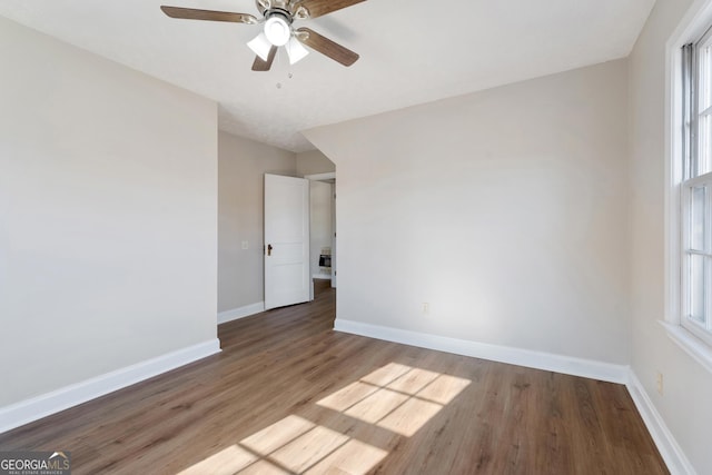 spare room with a wealth of natural light, ceiling fan, and hardwood / wood-style flooring