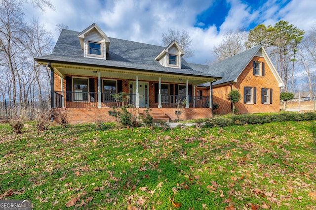 cape cod home featuring a front lawn and covered porch