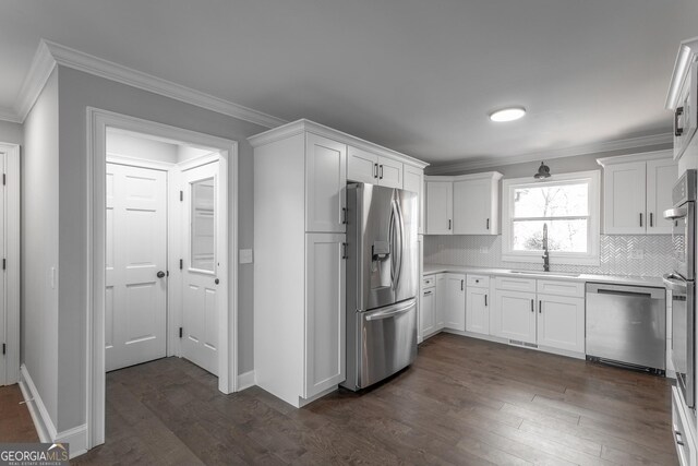 kitchen featuring backsplash, dark hardwood / wood-style floors, ornamental molding, appliances with stainless steel finishes, and white cabinetry