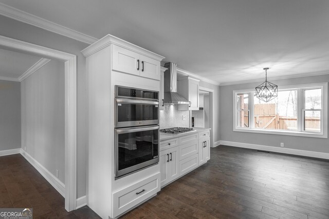 kitchen featuring wall chimney range hood, dark hardwood / wood-style flooring, decorative backsplash, white cabinets, and appliances with stainless steel finishes