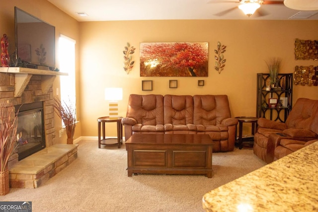 living room featuring ceiling fan, a stone fireplace, and light carpet