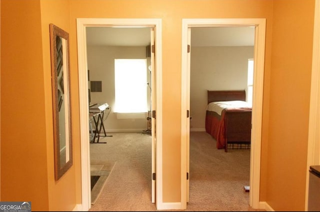 corridor featuring baseboards and carpet flooring