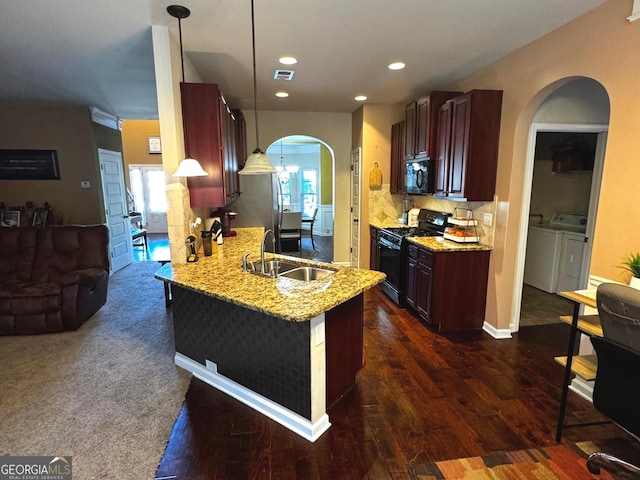 kitchen with decorative backsplash, a peninsula, arched walkways, black appliances, and a sink