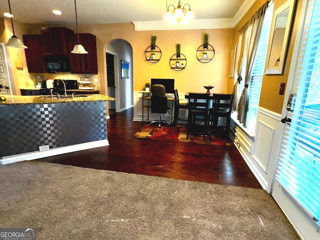 dining area featuring dark wood finished floors, arched walkways, and ornamental molding