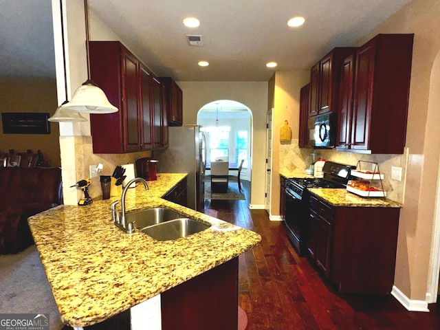 kitchen featuring visible vents, a peninsula, arched walkways, a sink, and black appliances