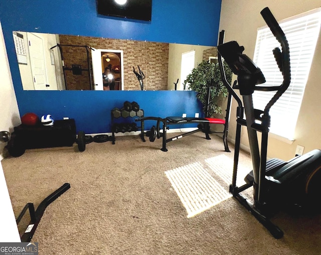 exercise room with carpet flooring and brick wall