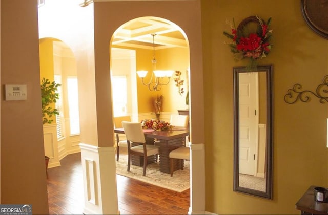 dining area featuring an inviting chandelier, crown molding, dark hardwood / wood-style flooring, and ornate columns