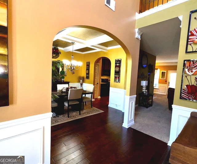 interior space with visible vents, a chandelier, a wainscoted wall, hardwood / wood-style floors, and coffered ceiling