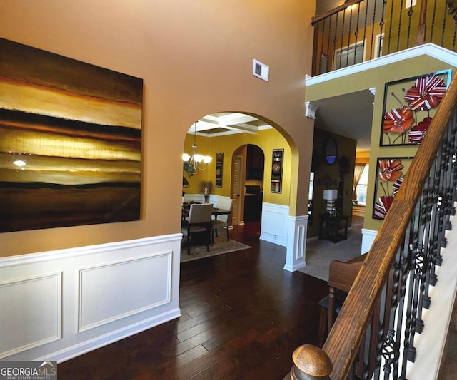 interior space with visible vents, a chandelier, stairs, arched walkways, and wood-type flooring