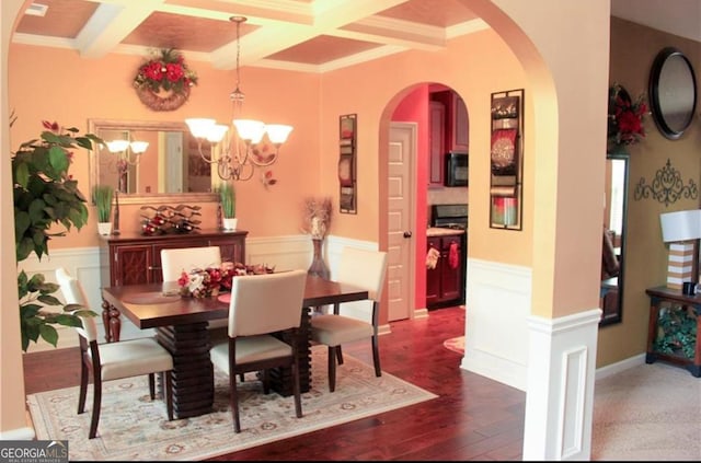 dining area with dark hardwood / wood-style flooring, a chandelier, ornamental molding, and beam ceiling