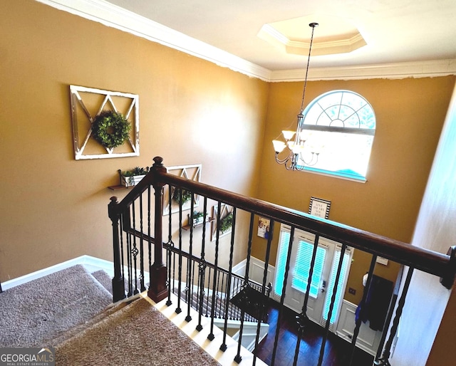 stairway with baseboards, a raised ceiling, an inviting chandelier, and ornamental molding