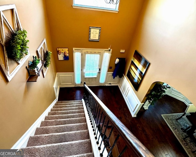 staircase with a high ceiling, baseboards, and wood finished floors