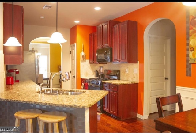 kitchen with appliances with stainless steel finishes, hanging light fixtures, light stone countertops, kitchen peninsula, and tasteful backsplash