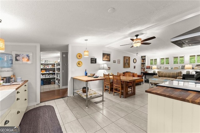 kitchen with wood counters, pendant lighting, vaulted ceiling with beams, and a textured ceiling