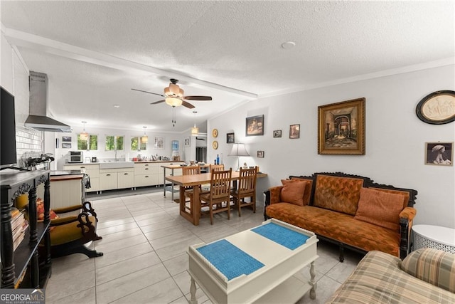 tiled living room with a textured ceiling, ceiling fan, crown molding, sink, and lofted ceiling with beams