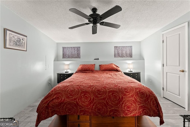 bedroom with ceiling fan, a textured ceiling, and light hardwood / wood-style flooring