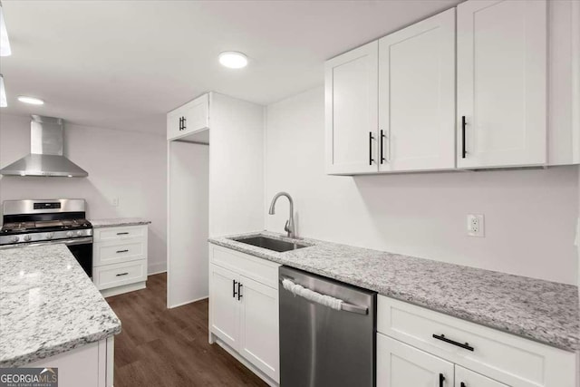 kitchen with wall chimney range hood, sink, dark hardwood / wood-style floors, appliances with stainless steel finishes, and white cabinetry