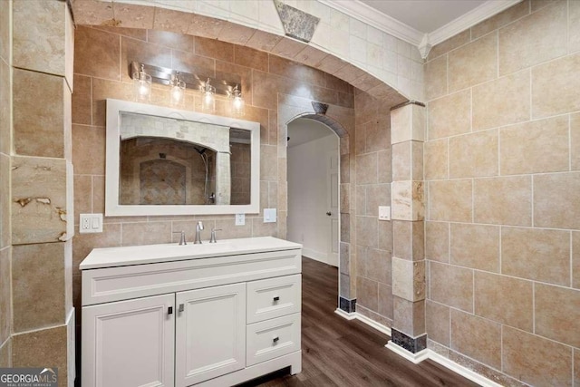 bathroom with hardwood / wood-style floors, vanity, tile walls, and ornamental molding