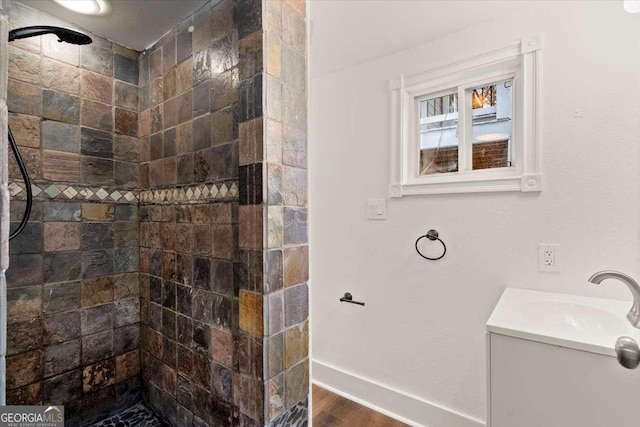 bathroom with a tile shower, vanity, and hardwood / wood-style flooring