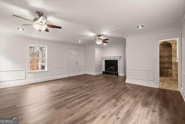 unfurnished living room with hardwood / wood-style floors, ceiling fan, ornamental molding, and a fireplace