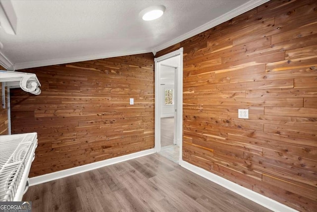 hallway featuring wood-type flooring, ornamental molding, and wood walls