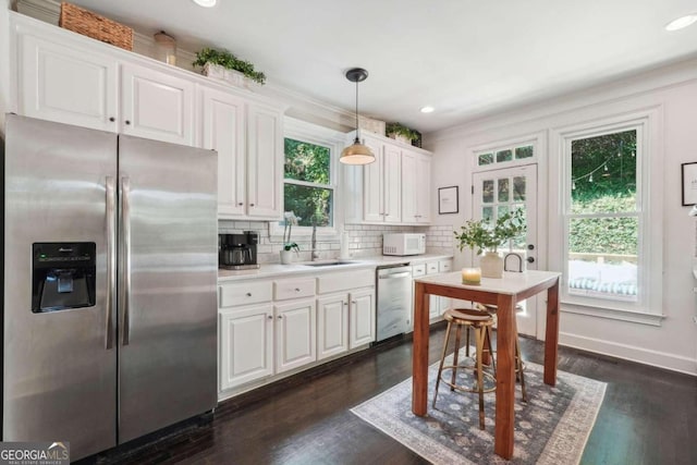 kitchen with white cabinets, appliances with stainless steel finishes, plenty of natural light, and pendant lighting