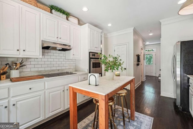 kitchen with dark hardwood / wood-style floors, white cabinetry, crown molding, and appliances with stainless steel finishes