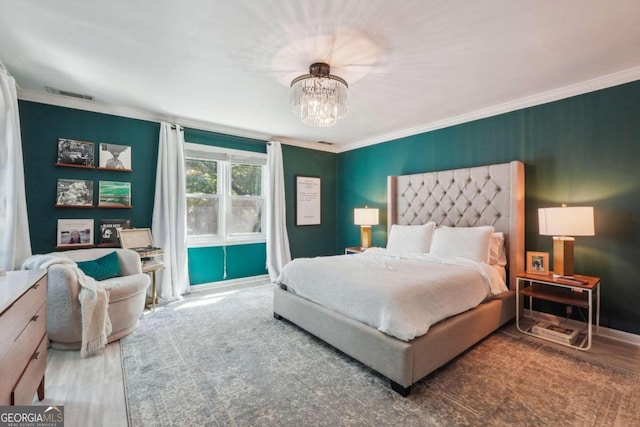 bedroom featuring hardwood / wood-style flooring, an inviting chandelier, and ornamental molding