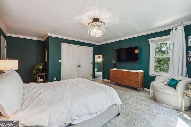 bedroom featuring crown molding, a closet, a chandelier, and light wood-type flooring