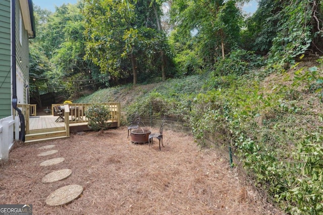 view of yard with a wooden deck and an outdoor fire pit