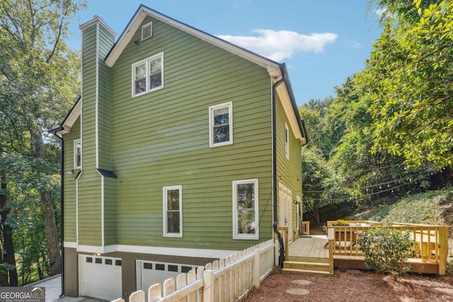 view of side of property featuring a garage and a wooden deck