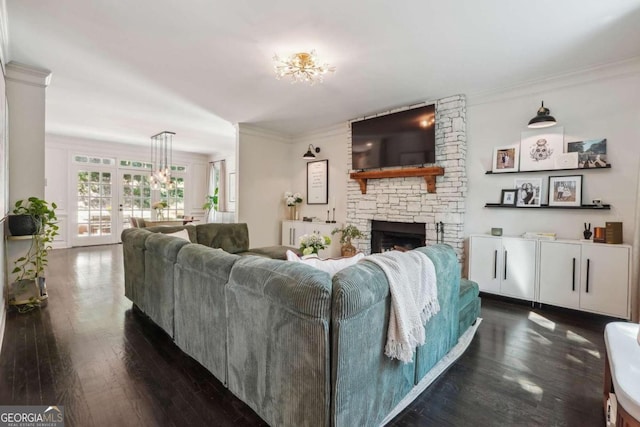 living room featuring crown molding, a fireplace, dark wood-type flooring, and a notable chandelier