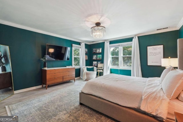 bedroom with hardwood / wood-style floors, crown molding, and a chandelier