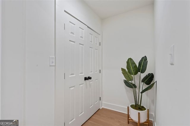 corridor featuring baseboards and light wood finished floors