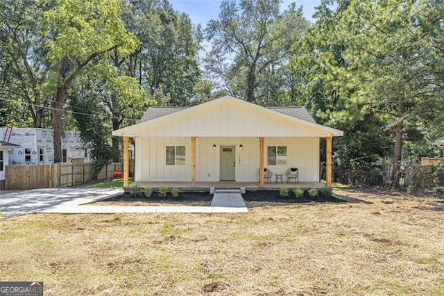 view of front facade featuring covered porch, fence, and a front lawn