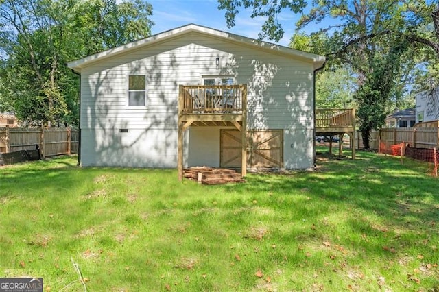 back of house featuring a fenced backyard, a deck, and a yard