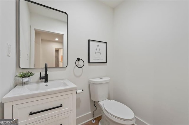 bathroom featuring baseboards, vanity, and toilet