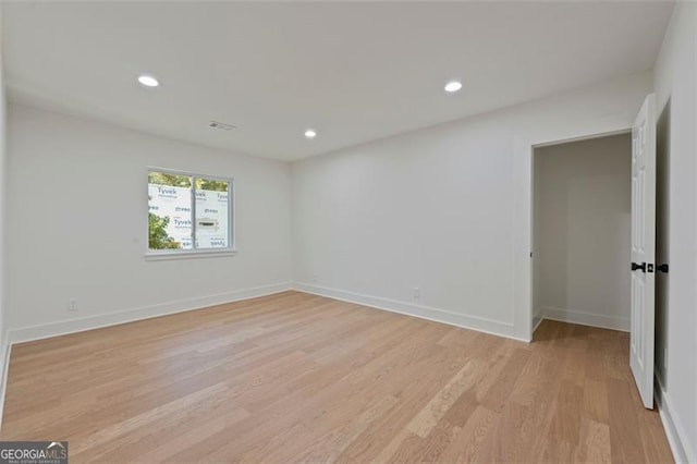 spare room featuring baseboards, light wood-type flooring, visible vents, and recessed lighting