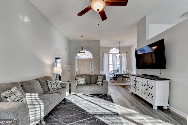 living room featuring hardwood / wood-style floors, ceiling fan with notable chandelier, and a textured ceiling