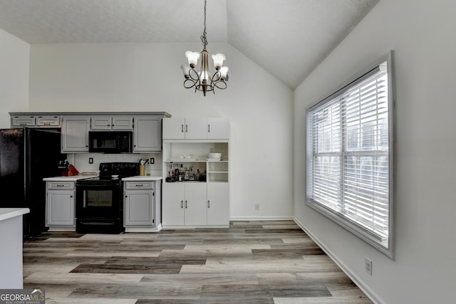 kitchen with pendant lighting, vaulted ceiling, light hardwood / wood-style floors, gray cabinets, and black appliances